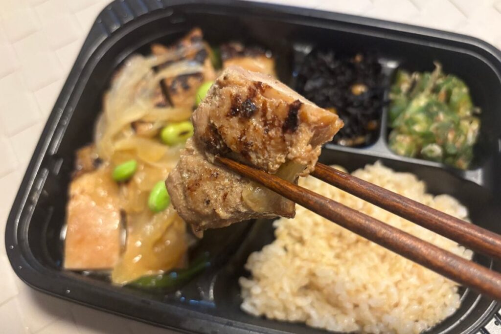 てりてりに焼いた鶏もも肉の生姜焼きと香り引き立つ炙り枝豆　箸で持ったところ